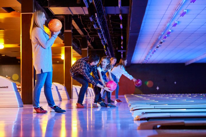 Group of people bowling in glowing lights.