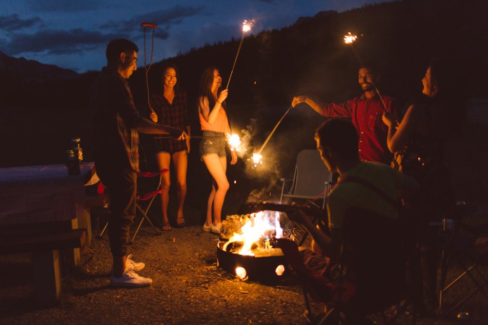 group of friends light sticks in a campfire at two jack lake banff national park