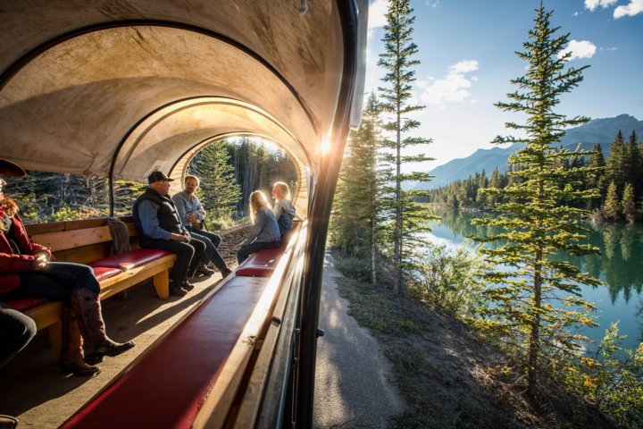 Family riding inside a covered wagon along the Bow River in Banff National Park.