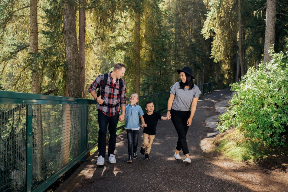 mom and dad with two boys walk along a trail in Banff National Park
