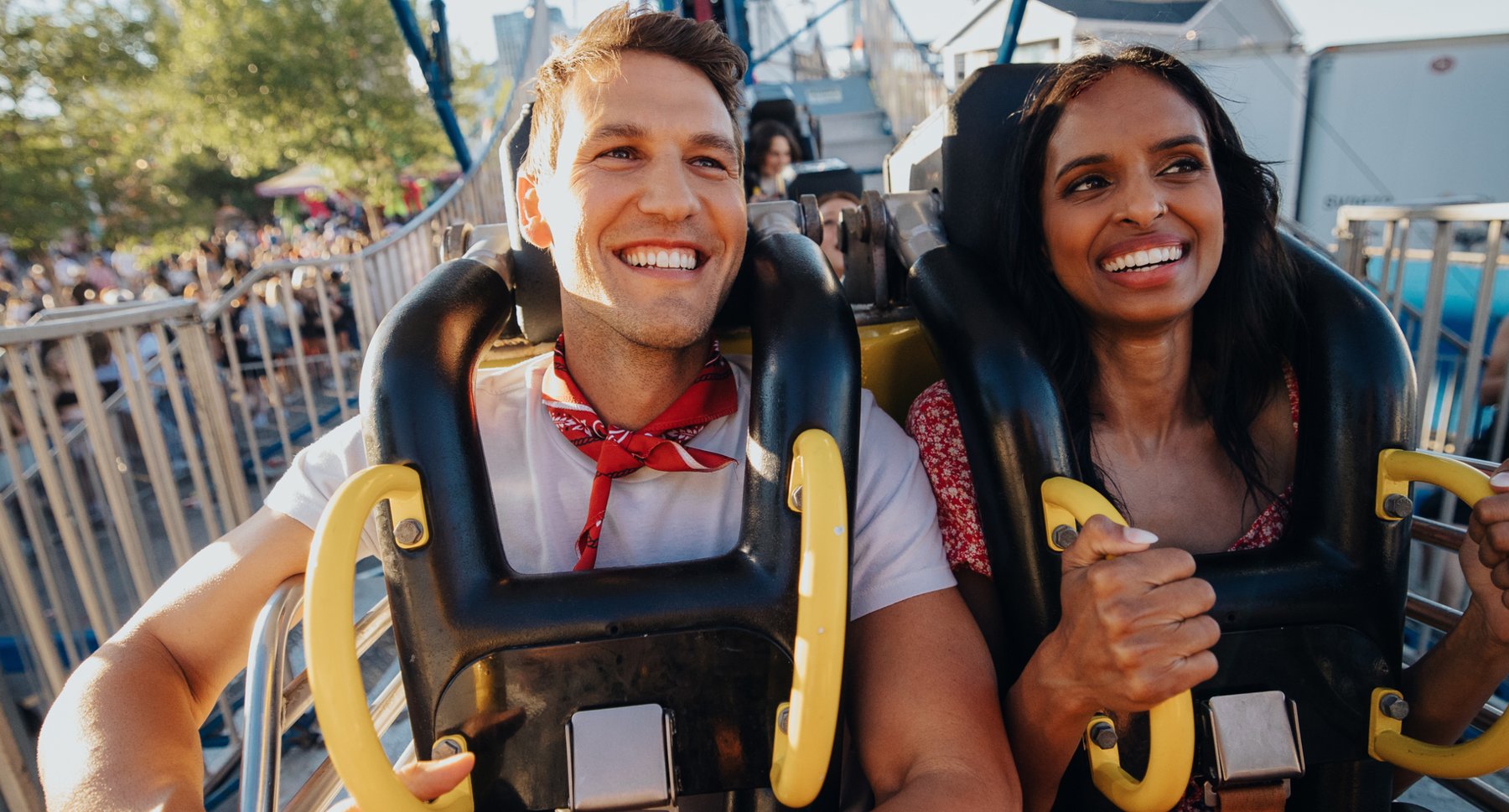 A man and women smiling while riding an midway ride.