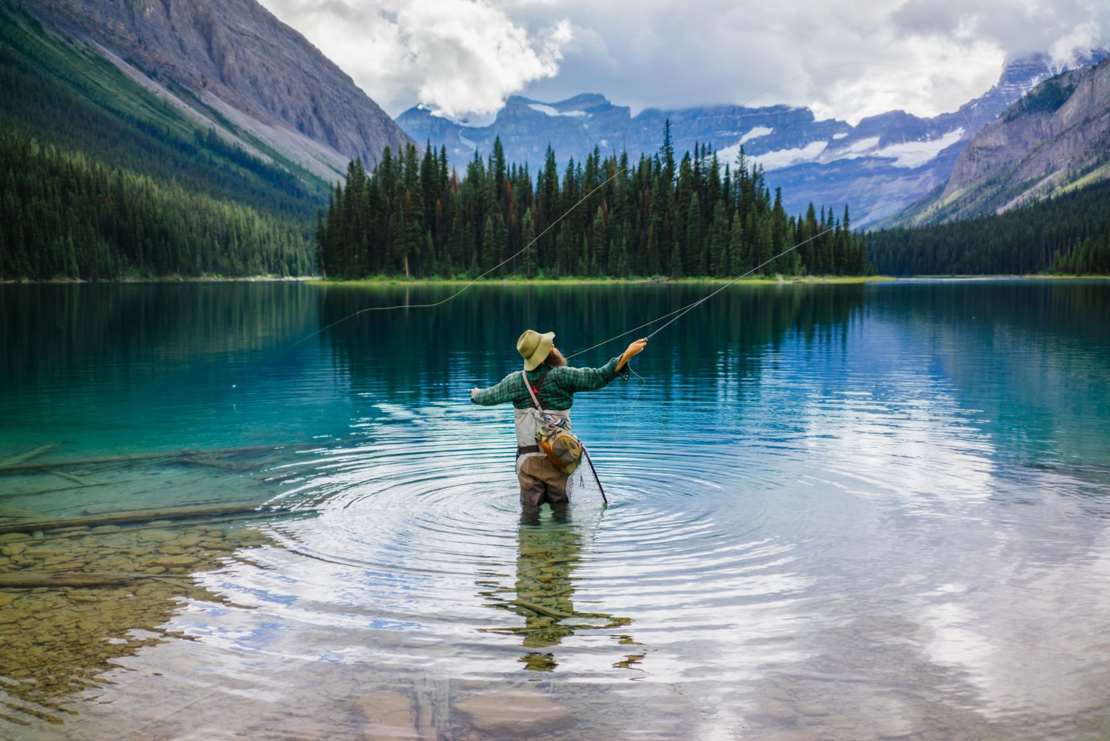 Scenic shot of a man fly fishing at Marvel Lake with a mountain view