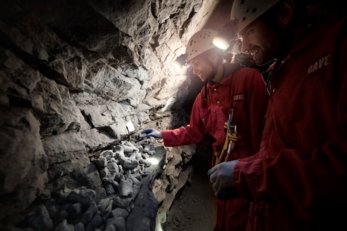Two people exploring a cave with headlamps
