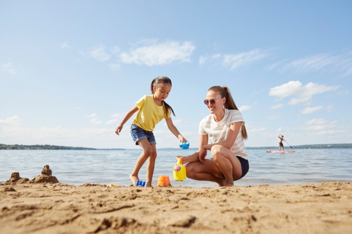 Women and child play in the sand with toys at Sylvan Lake.