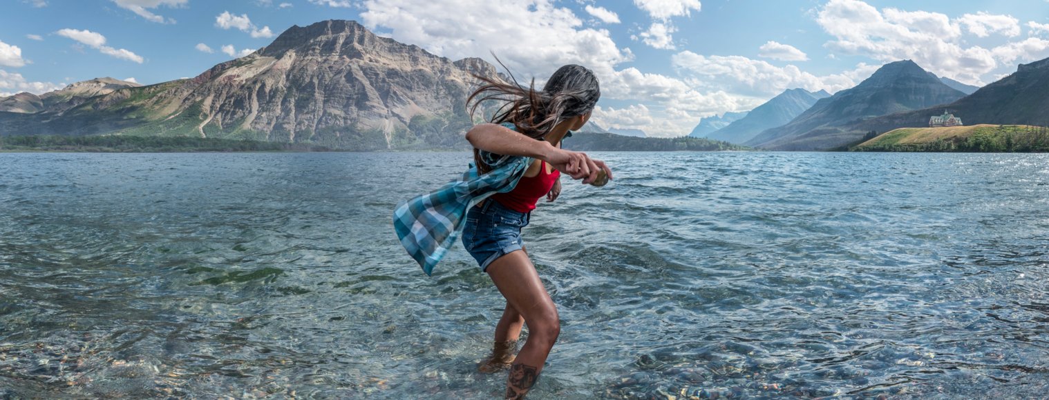 Person skipping rocks into Driftwood Beach in Waterton Lakes National Park.