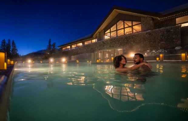 Couple enjoying the Fairmont Jasper Park Lodge outdoor pool at dusk.