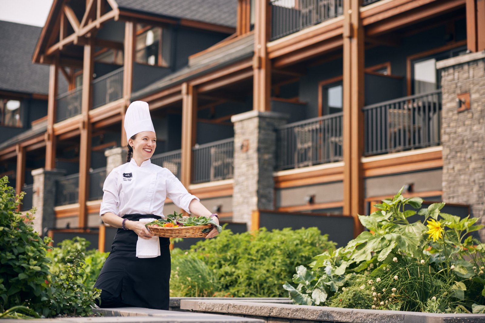 A chef walking outside of the The Malcolm Hotel in Canmore holding a tray of food.