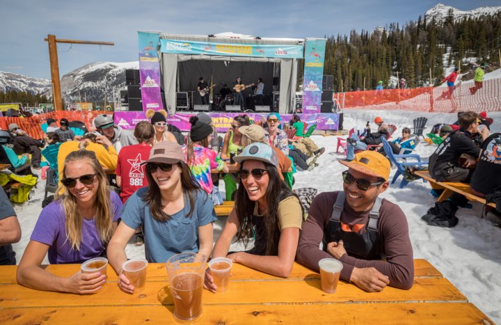 Friends enjoying drinks and food while listening to live music, after Spring Skiing at Sunshine Village in Banff National Park