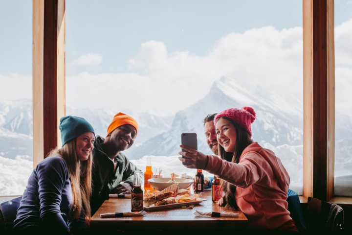 A group of skiers and snowboarders enjoying food and beer at the Cliffhouse Bistro in Mt. Norquay.