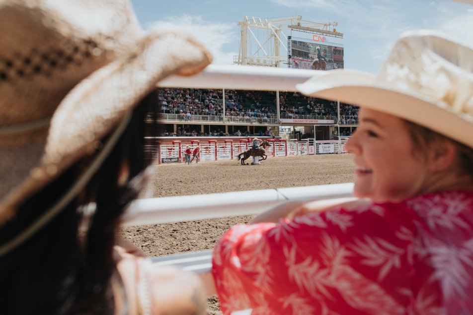 Stampede-goers at the rodeo watch a barrel racer compete.