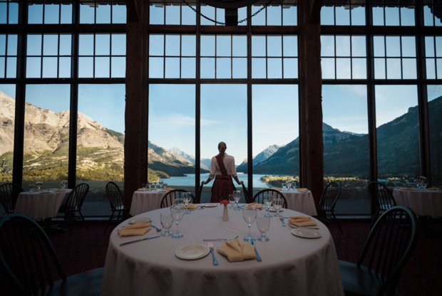 Wide angle view of women looking out large windows to mountain view from a hotel dining room.