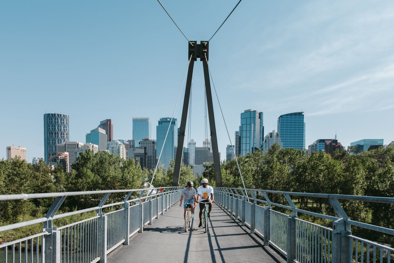 Two people cycling across the Prince's Island Bridge in Calgary.