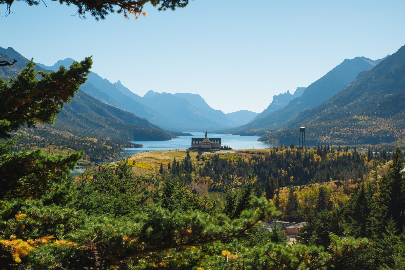 Scenic view of the Prince of Wales Hotel surrounded by forest and mountains in Waterton Lakes National Park.
