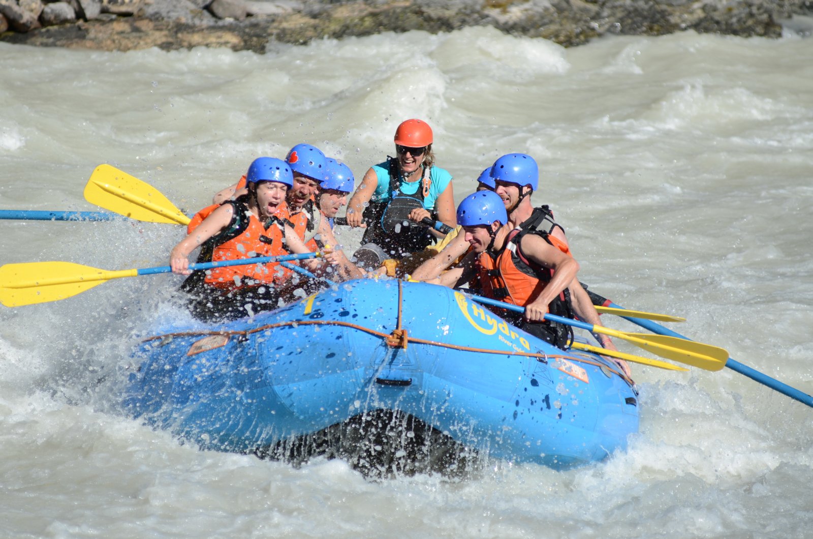 A group with a mix of different facial expressions as they whitewater raft down a river.