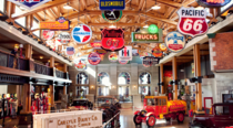 Interior view of a museum filled with old cars and gas station signage.