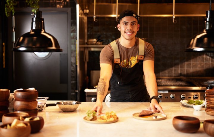 Smiling chef showing off his dishes in a contemporary kitchen
