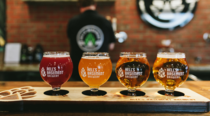 A beer flight with four samples of delicious beers displayed attractively on a wooden plank