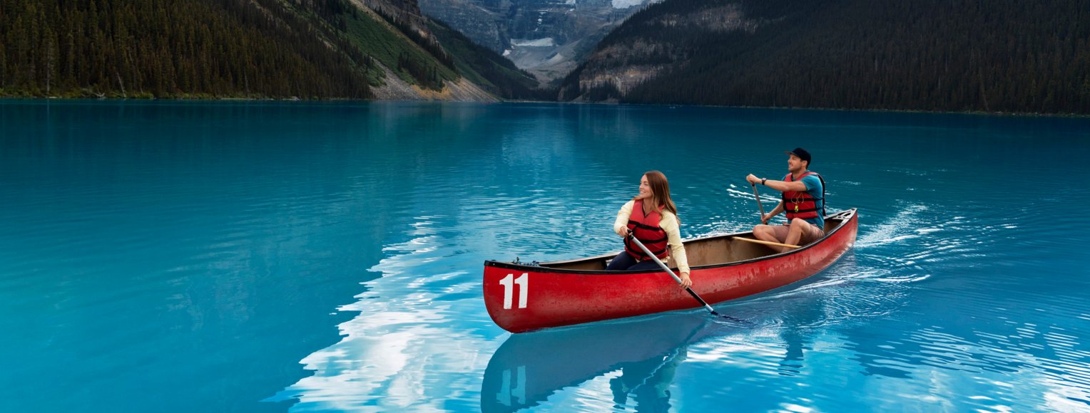 A couple paddles across the turquoise waters of Lake Louise.